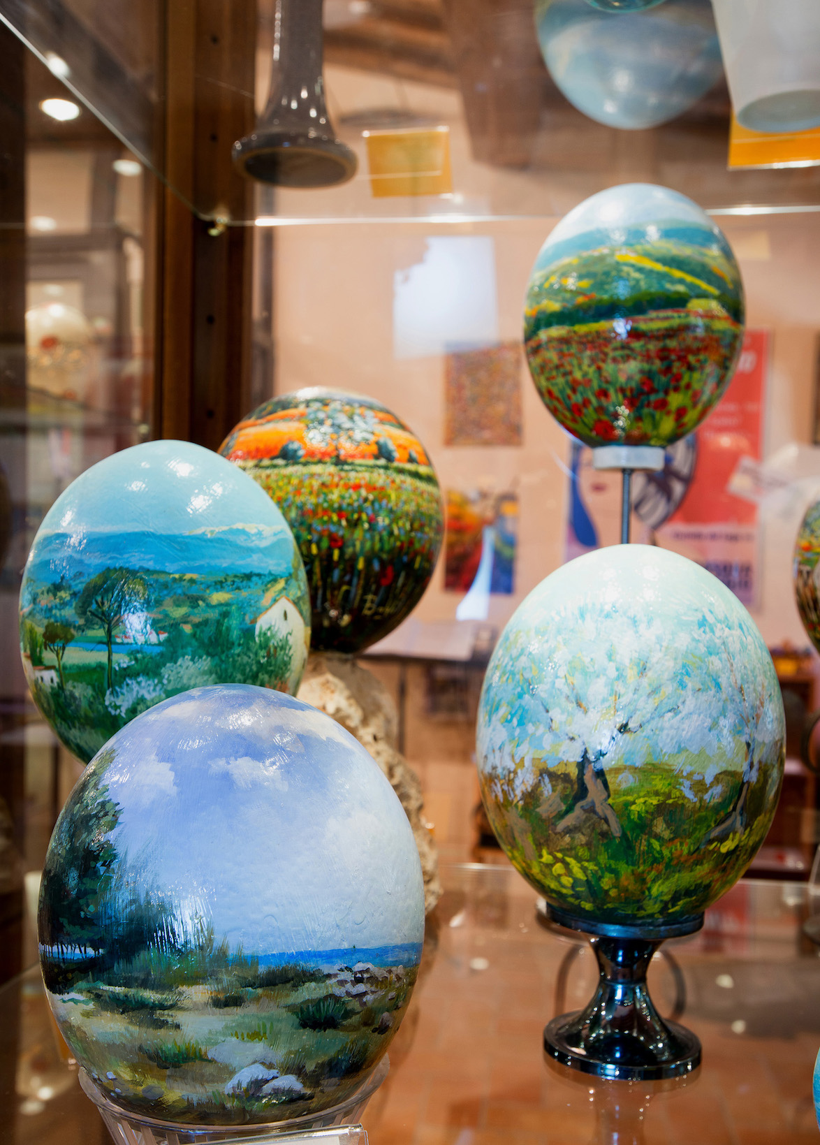 Hand-painted artistic eggs featuring natural landscapes, displayed in a showcase at the Ovo Pinto Museum in Civitella del Lago.