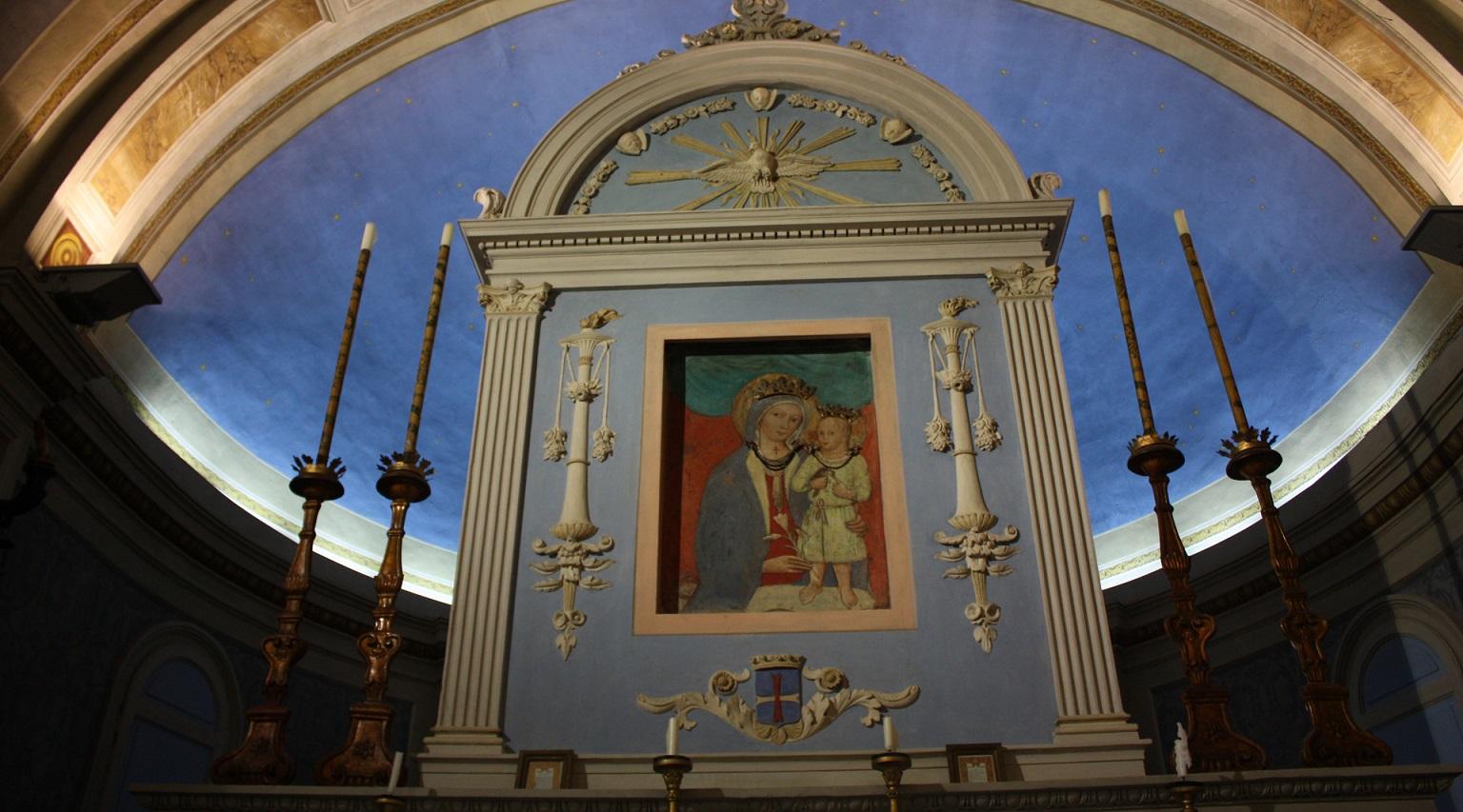 Altare con immagine della Madonna col Bambino, incorniciata da colonne e candelieri, sotto una volta a semicerchio blu.