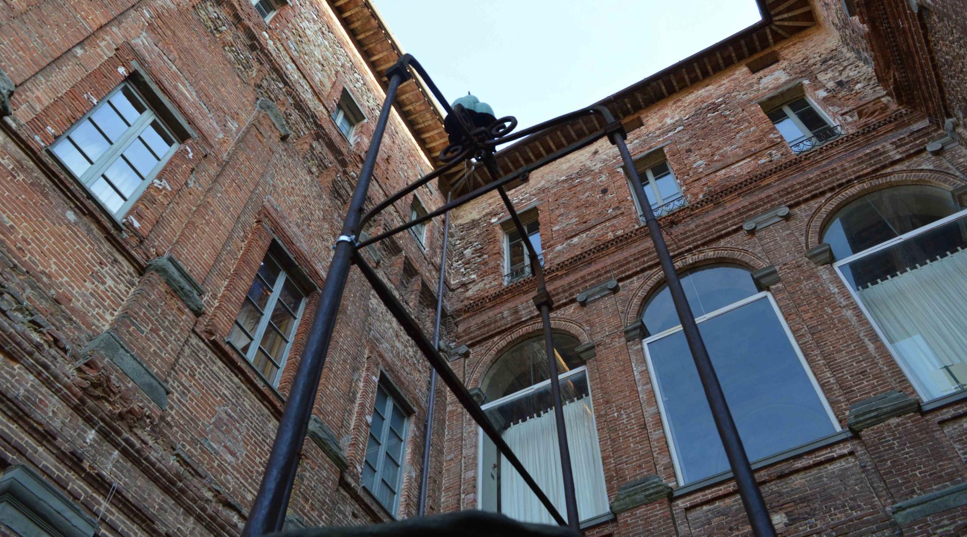 View from the courtyard looking upwards, with the well in the foreground. The windows of the upper floors overlook the courtyard, creating a harmonious overall view.