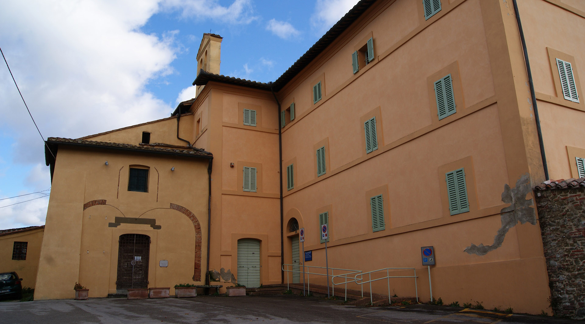 Panoramic view of the exterior of the Church of San Sebastiano, with its simple plastered façade, reflecting a modest and restrained architecture.