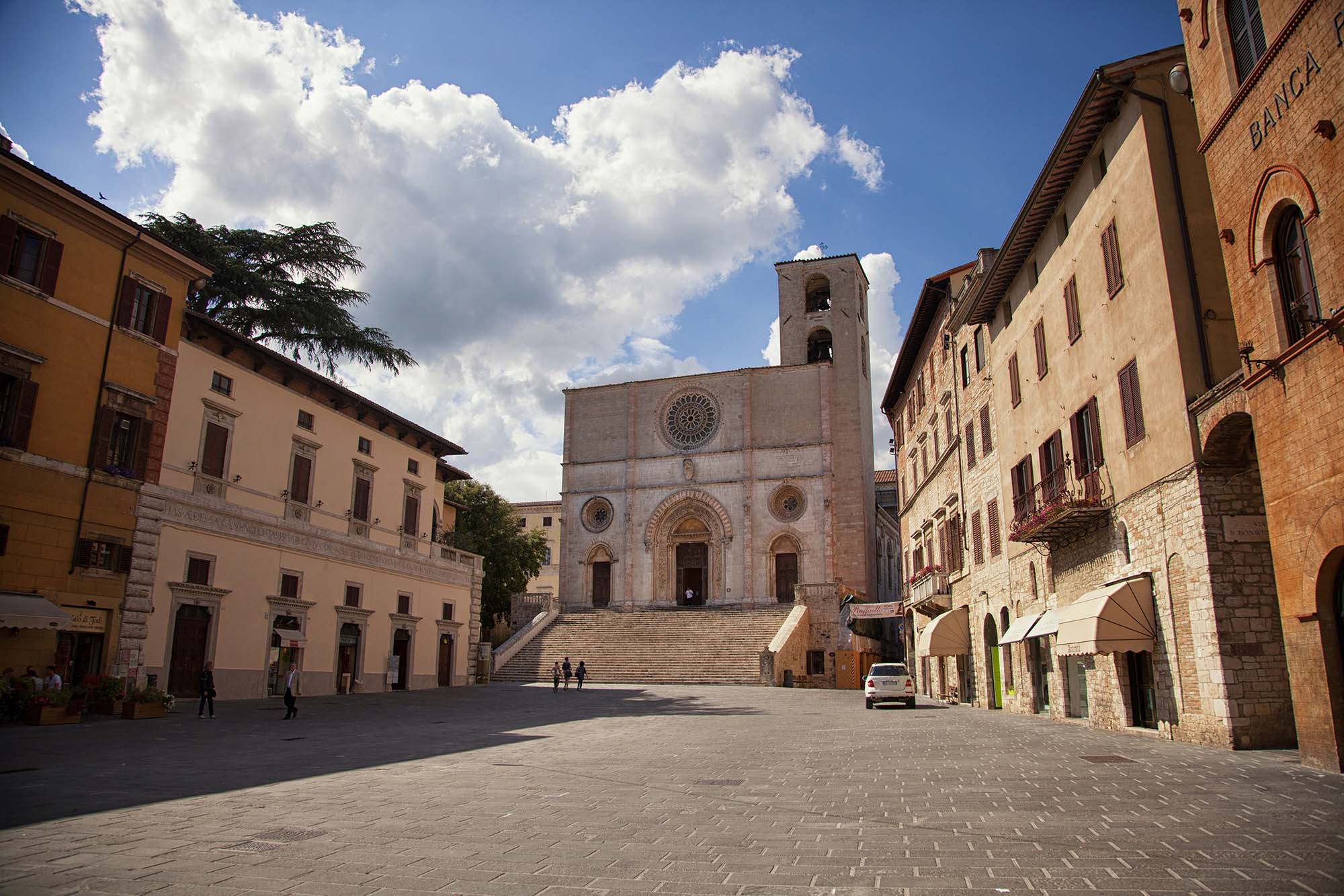 Piazza del Popolo a Todi con il Duomo romanico, la scalinata e la torre campanaria, circondata da palazzi storici.