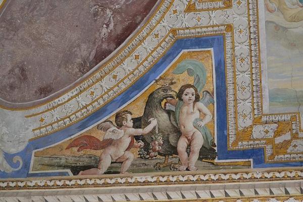 Affresco nel Castello di Giove con putti e un’aquila decorativa in una cornice dipinta.