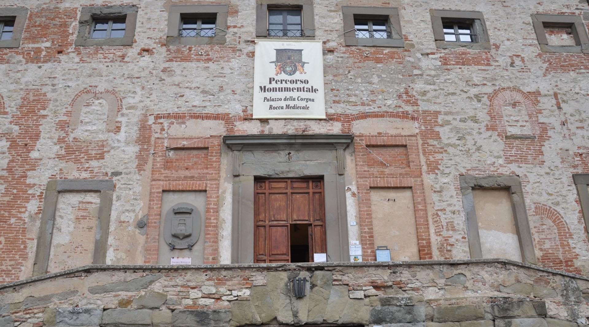 Façade of Palazzo della Corgna in Castiglione del Lago, with raised entrance, exposed brickwork and coat of arms.