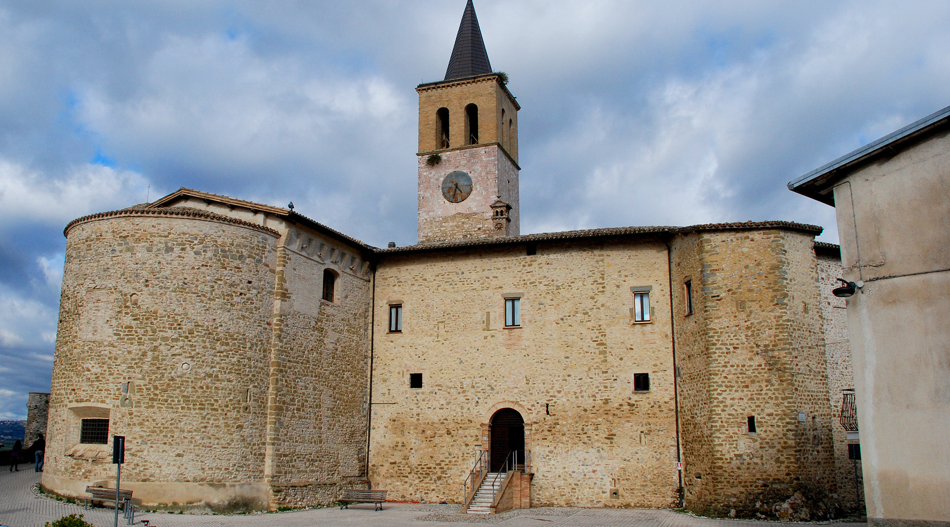Uno sguardo interno all’edificio, tra nicchie e dipinti L’interno della chiesa si presenta con un’unica navata ampia e luminosa, caratterizzata da un soffitto molto alto che accentua il senso di verticalità e solennità dello spazio sacro interno. In fondo alla navata, dove è conservato un affresco del 1508 staccato dalla parete originaria che raffigura la Madonna col Bambinoin una mandorla, si trovano due nicchie laterali: Prima nicchia di sinistra: i resti di affreschi di difficile lettura decorano le pareti laterali. Sulla sinistra è presente la tela che raffigura la Madonna Addoloratae san Gregorio Magno, con un cherubino che regge un cartiglio dove si legge la scritta “A sua maestà Carlo Martello Re di Francia”. Sull’altare è collocata una tela di XVII secolo realizzata da un pittore eugubino anonimo, dove si vedono le figure di san Gregorio Magno, sant’Antonio Abatee santa Caterina d’Alessandria. Sopra l’altare troneggia una statua lignea resa molto scura dal tempo, che probabilmente raffigura santa Marina; Seconda nicchia di sinistra: corrisponde probabilmente all’abside originale della chiesa primitiva. La volta a crociera è decorata da costolonature a fasce policrome che spiccano su uno sfondo scuro a motivi floreali. Sulla parete di fondo è presente un affresco del XV secolo che raffigura otto santi di difficile lettura. Al centro della navata, si trovano due altari: Altare mediano di destra: ospita la statua di santa Marina, raffigurata mentre tiene in braccio il bimbo da lei allevato; Altare mediano di sinistra: è presente la tela seicentesca con la Madonna del Rosarioaffiancata da san Domenico, santa Caterina da Siena, san Francesco d’Assisi e san Carlo Borromeo, opera di Giovanni Francesco Romanelli. Il presbiterio, rialzato da gradini e introdotto da un arco impostato su colonne, precede l’altare maggiore e custodisce alcune delle opere più preziose della chiesa: Nicchia di destra: pregevole affresco del 1512 che reca la firma di Tiberio di Assisi, discepolo del Perugino, riportato alla luce nel 1896. Nel registro inferiore sono raffigurati l’arcangelo Raffaele che tiene per mano il giovane Tobiolo, seguito da santa Caterina e, sulla destra, san Silvestro I Papa in abiti pontificali che sovrasta il dragone ucciso al Monte Soratte. Nella calotta è raffigurato l’Eterno benedicente con il globo nella mano e un arco iridescente, circondato da nubi dorate e affiancato da nove serafini e due angeli. Altare di sinistra: dedicato alla Madonna del Soccorso, custodisce una delle opere più interessanti dell'edificio: la Vergine del Soccorso. Abbigliata in un ampio manto stellato, la Madonna libera un bambino dalle grinfie del demonio. La tradizione popolare racconta che l’immagine nasce da un episodio realmente accaduto: una madre, esasperata dal non riuscire ad addormentare il figlio, arrivò ad invocare il diavolo. Quando però questo apparve, pentita, implorò l’aiuto della Madonna, che intervenne salvando il bambino. Ai piedi sono raffigurati anche la madre e il letto del piccolo. L’opera, attribuita a Melanzio da Montefalco, “Sancta Maria populo castri Ritaldo, 1509”. In fondo alla chiesa si trovavano l’altare che è stato demolito e un crocifisso del Trecento, attualmente trasferito in sacrestia, mentre fino al 1745 dietro l’altare maggiore era presente un coro ligneo di fattura gotica. Una santa sotto mentite spoglie Nata in Bitinia, nell’attuale Turchia, nella prima metà dell’VIII secolo, Marina trascorse una breve vita segnata dal dolore. Rimasta orfana di madre, il padre Eugenio si ritirò nel monastero di Kanoubine. Per non separarsi da lui, vestì l’abito monastico assumendo il nome di Marino, e celò la propria identità per poter condividere la vita del convento. Durante una sosta in locanda con alcuni confratelli, fu ingiustamente accusata della violenza ricevuta dalla figlia dell’oste ma, anziché difendersi, accettò in silenzio la colpa. Fu quindi espulsa dal monastero e costretta ad accudire il neonato. Dopo anni di umiliazioni e fatiche i suoi confratelli, che non avevano mai creduto all’accusa, riuscirono a far riammettere il giovane Marino in convento, dove gli furono affidati i lavori più umili. Consumata dalle fatiche e dalle privazioni, Marina si spense in giovane età. Solo allora, preparando il corpo per la sepoltura, i monaci scoprirono la sua vera identità, ricevendo la prova della sua innocenza, e compresero come la giovane aveva rinnegato se stessa e sopportato in silenzio l’ingiusta accusa. Al suo capezzale giunse anche la figlia del locandiere che, tormentata dal rimorso, ottenne perdono e guarigione. Già in vita si iniziò a parlare della santità di Marina, ma dopo la morte la sua devozione si diffuse rapidamente e numerosi eventi miracolosi furono attribuiti alla sua intercessione. Il suo corpo, inizialmente sepolto nel monastero, fu condotto a Venezia, dove ancora oggi è conservato.