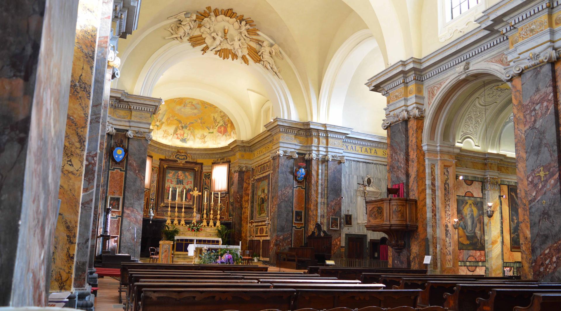 Intérieur de l'église avec la nef centrale, riche en œuvres d'art. On voit l'autel, la chaire et les bancs destinés aux fidèles.