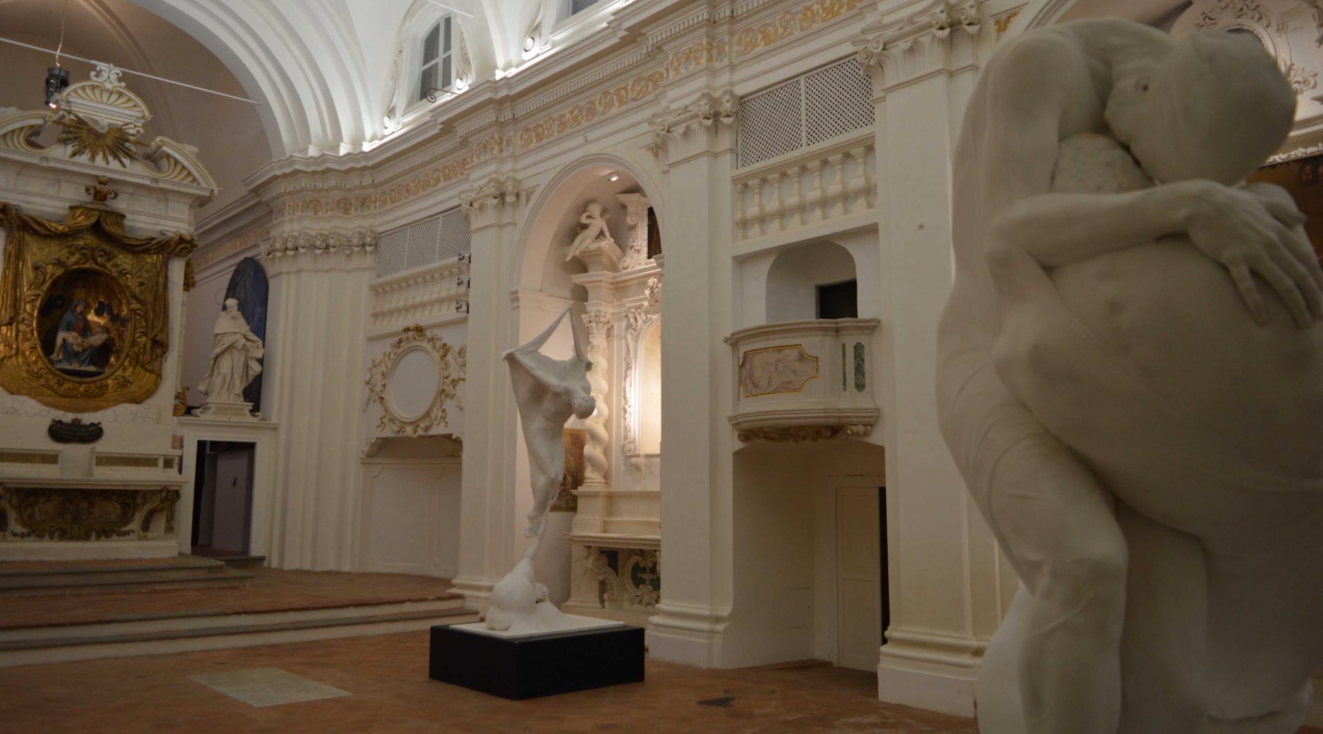 In the foreground, two sculptures dominate the scene, while brick arches line the sides. In the background, the Baroque altar stands out, with its refined sculptures in the Bernini style.