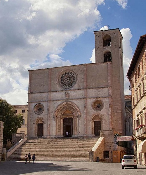Piazza del Popolo in Todi with the Romanesque Cathedral, the staircase, and the bell tower, surrounded by historic buildings.