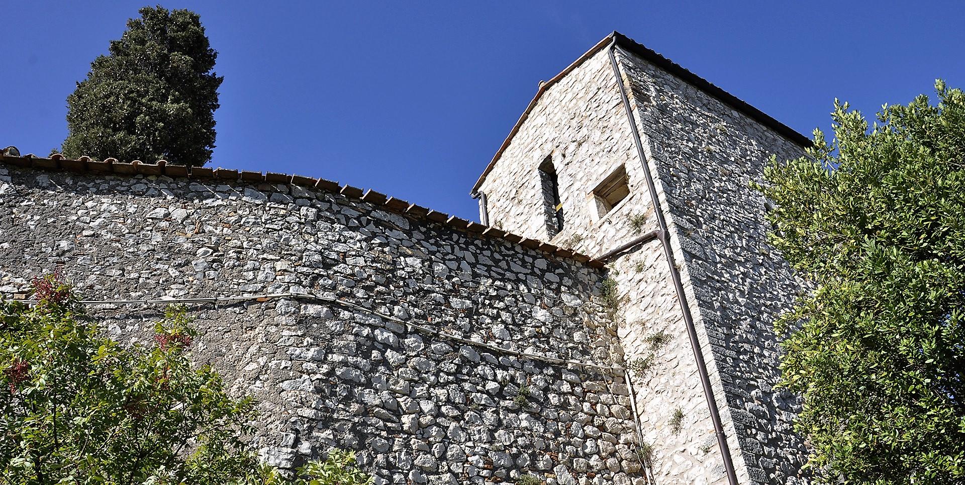 Stone corner tower of Castello del Poggio with fortified walls and clear sky in the background.