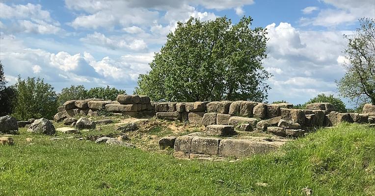 Remains of stone structures built with large blocks at the archaeological site of Urvinum Hortense, set in a natural landscape.