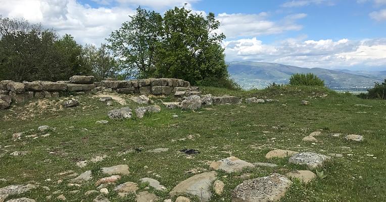 Archaeological area of Urvinum Hortense with stone wall remains overlooking the surrounding valley.