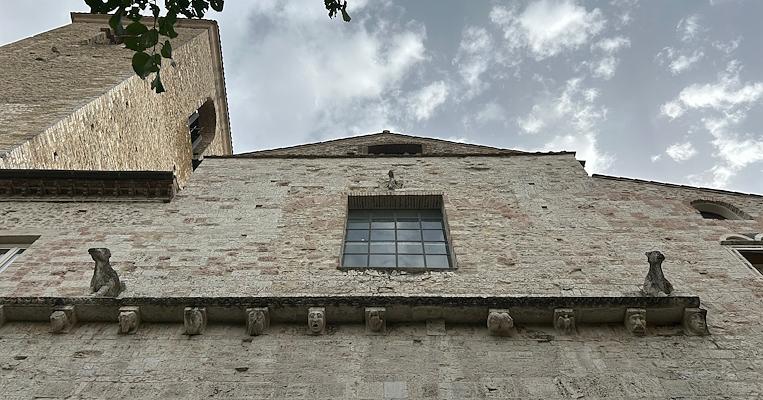 Vista dal basso della facciata dell'ex chiesa di San Domenico a Narni, ora Auditorium Bortolotti. La facciata in pietra è caratterizzata da un'ampia finestra rettangolare e da una cornice trasversale di maschere che fungono da cariatidi, mentre ai lati della finestra, sopra la cornice, sono presenti due leoni in pietra.