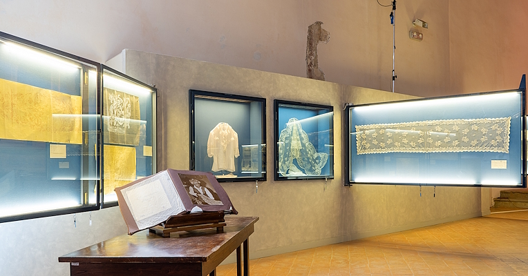 Display cases containing tulle artifacts and historical documents. In the foreground, an open book on a table with a photograph.