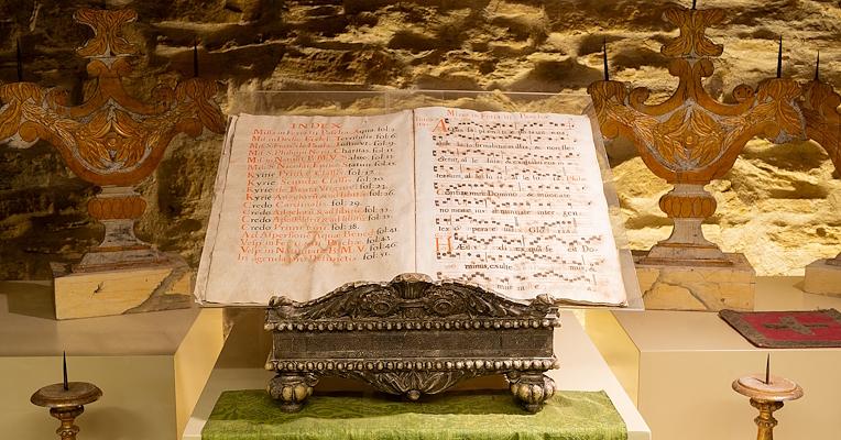 Ein antikes Notenpult mit Notenblättern von liturgischen Gesängen, mit gut sichtbaren Noten und Alterserscheinungen.