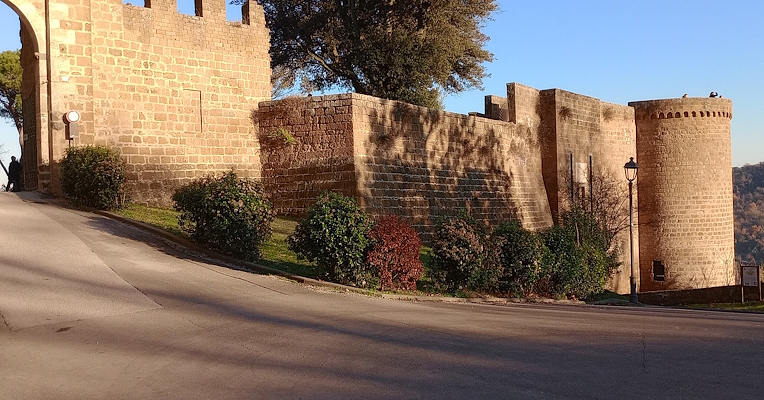 Albornoz Fortress of Orvieto at sunset, with tuff stone walls, a round tower, and the main entrance