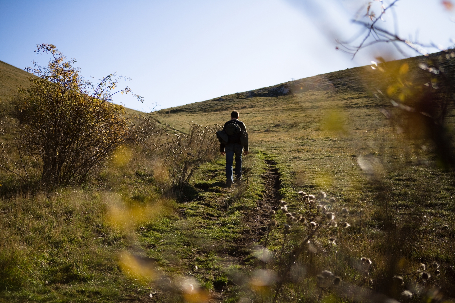A man walks on open mountain terrain in Assisi with trekking gear