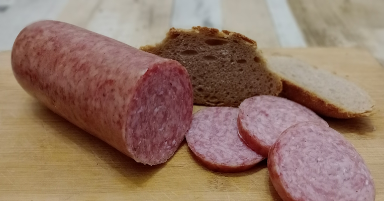 A ciauscolo next to three slices of pink cured meat and two slices of bread