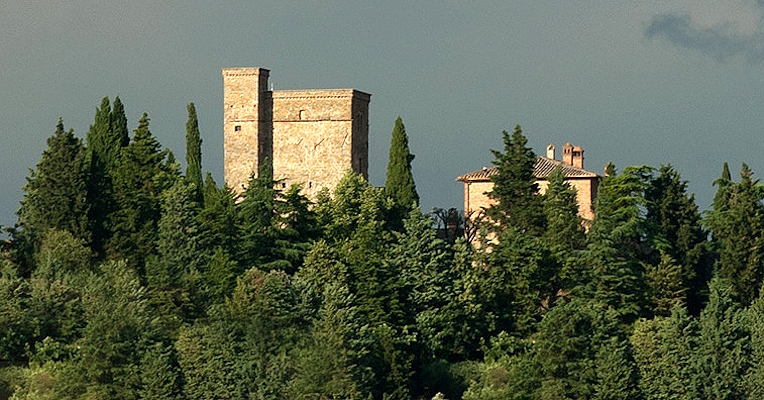Au loin, les tours de Rocca Monaldi se dressent au-dessus d’un panorama de forêts denses, créant une scène spectaculaire.