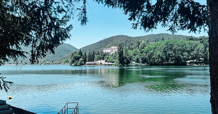 Lago di Piediluco con una scala e una barca sulla riva. Sullo sfondo, verdi colline si riflettono sulla superficie del lago