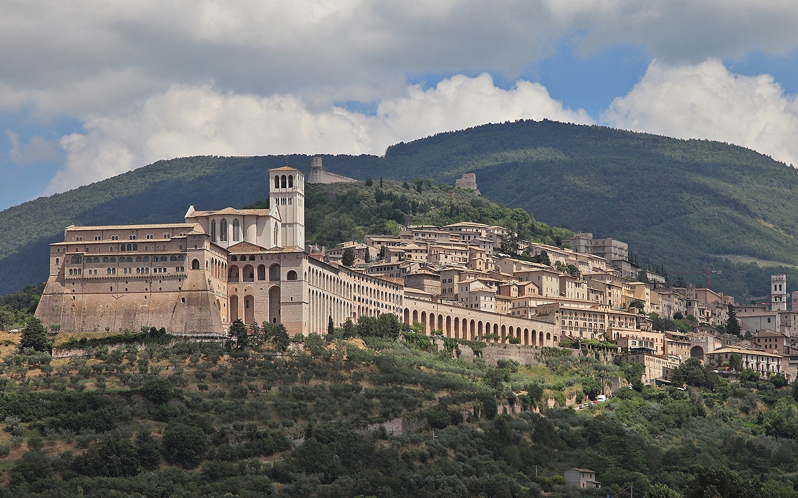 Vue panoramique d’Assise avec la basilique Saint François et les bâtiments historiques au premier plan, avec le mont Subasio à l’arrière-plan