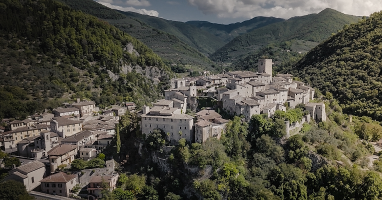 View of Arrone, a medieval village perched on a hill surrounded by mountains.