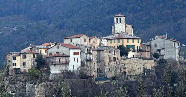 View of the medieval village of Papigno, with stone houses and a bell tower, nestled among the wooded Umbrian hills.