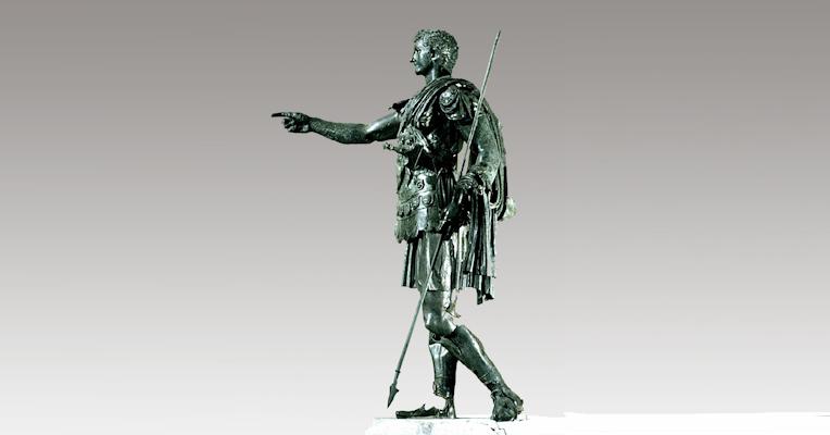 Full-length bronze statue of Germanicus, wearing armour and a cloak, with one arm extended pointing forward and a spear in the other hand.