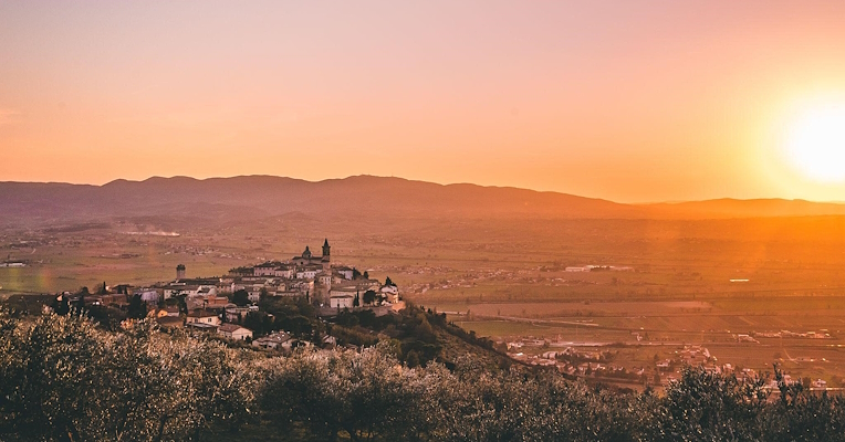 Panorama de Trevi avec le soleil couchant qui illumine la vallée et les oliveraies environnantes.