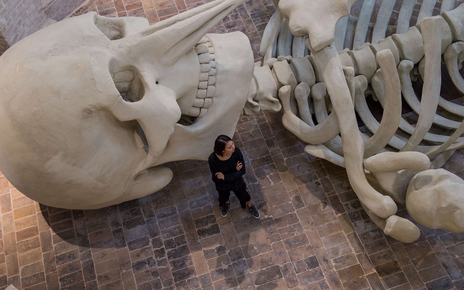 Scheletro gigante installato in una chiesa sconsacrata, tra luci soffuse e architettura in mattoni