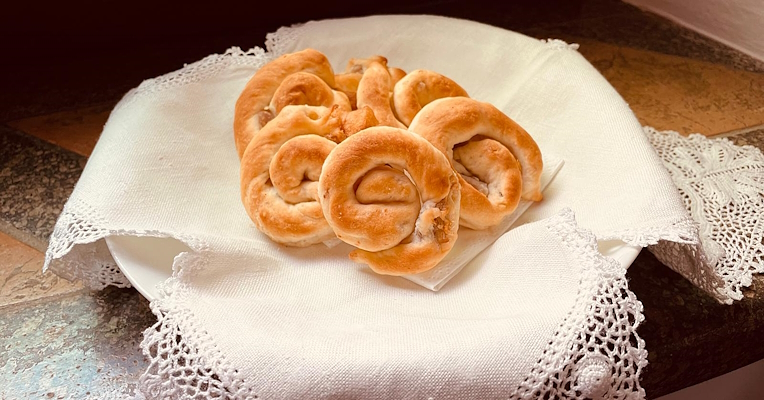 Plate of snail-shaped lumachelle from Orvieto, arranged on a white lace napkin placed on a stone windowsill.