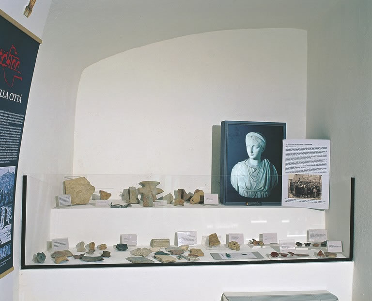 Display case with archaeological finds and information panels inside the Municipal Antiquarium of Otricoli.
