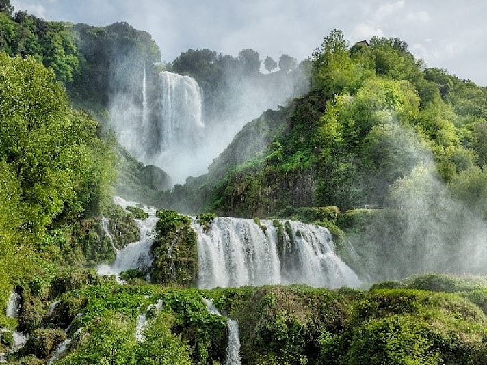 Veduta delle Cascate delle Marmore con più salti d’acqua tra la vegetazione e le rocce