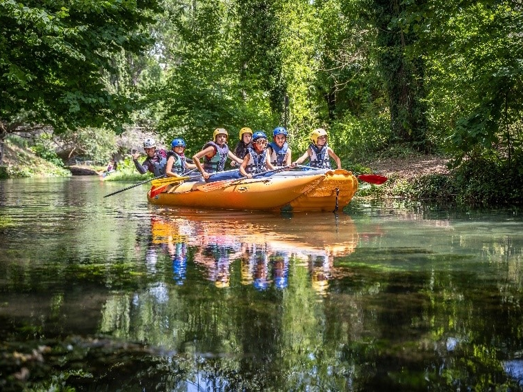 Gruppo di persone su un gommone durante un’escursione di rafting lungo il fiume Nera, circondati dalla vegetazione