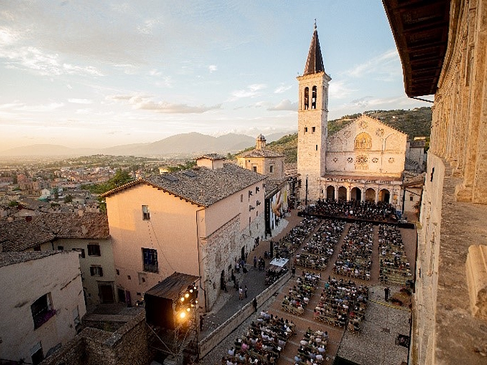 Vista dall’alto di Piazza Duomo a Spoleto durante il Festival dei Due Mondi, con il pubblico seduto davanti al palco allestito davanti al Duomo.