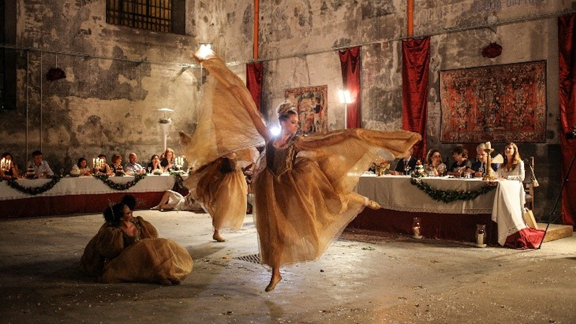 Des danseuses en costumes d’époque se produisent lors de l’événement « Gareggiare dei Convivi » de la Giostra della Quintana à Foligno, devant un public assis à table.