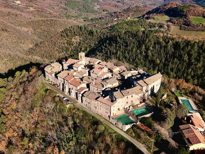 Veduta aerea del castello medievale di Macerino sui Monti Martani, immerso nei boschi umbri